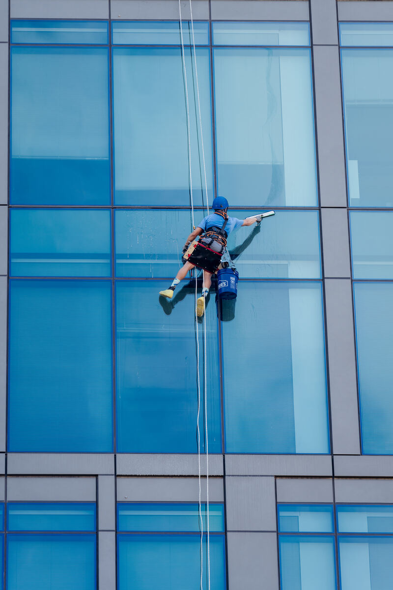 Atlas Facility Services rope access technician descending a commercial glass tower